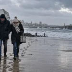 Vacances de février en Vendée : couple marche sur le remblai des Sables-d’Olonne, océan gris-bleu